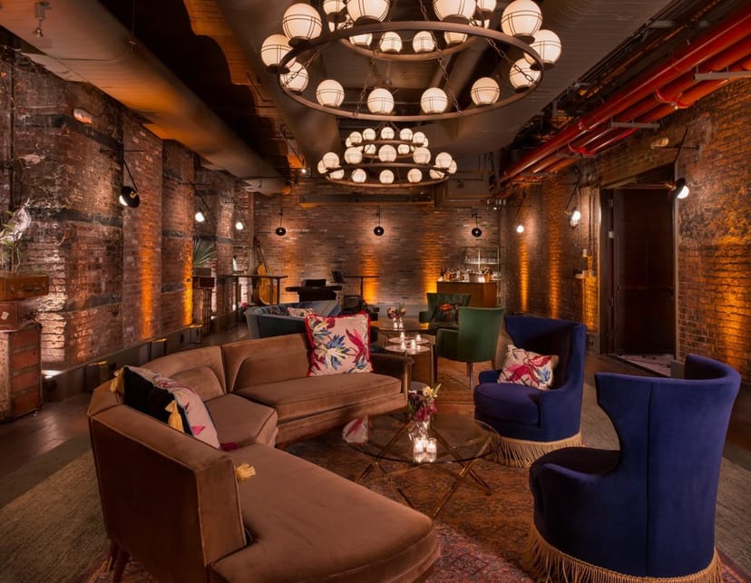 Stylish event space with exposed brick and chandelier, perfect for cocktail receptions.