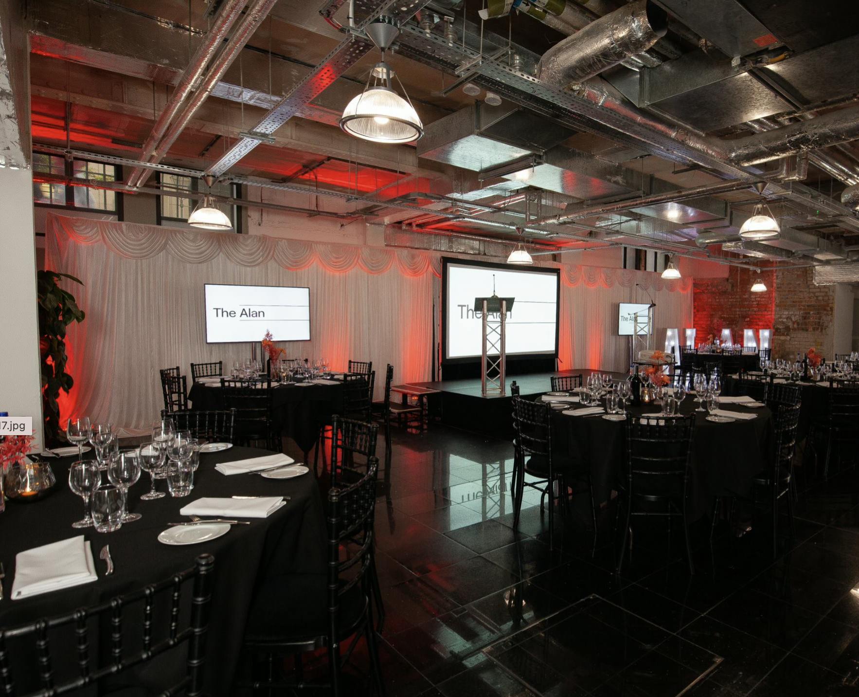 Elegant event space with black tables and white linens for corporate gatherings.