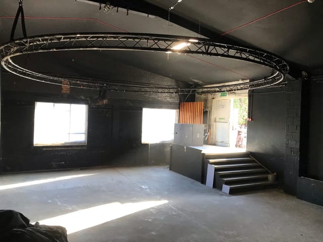 Versatile industrial event space with natural light and circular truss for presentations.