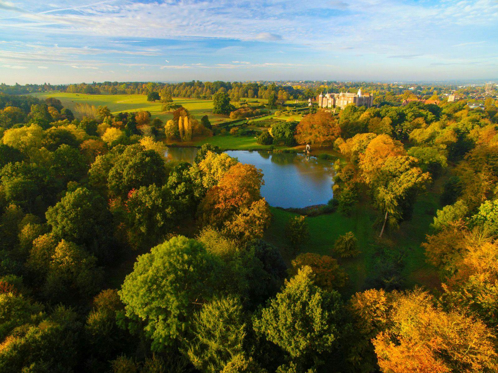 Outdoor event venue at Hatfield House with autumn foliage and serene lake backdrop.