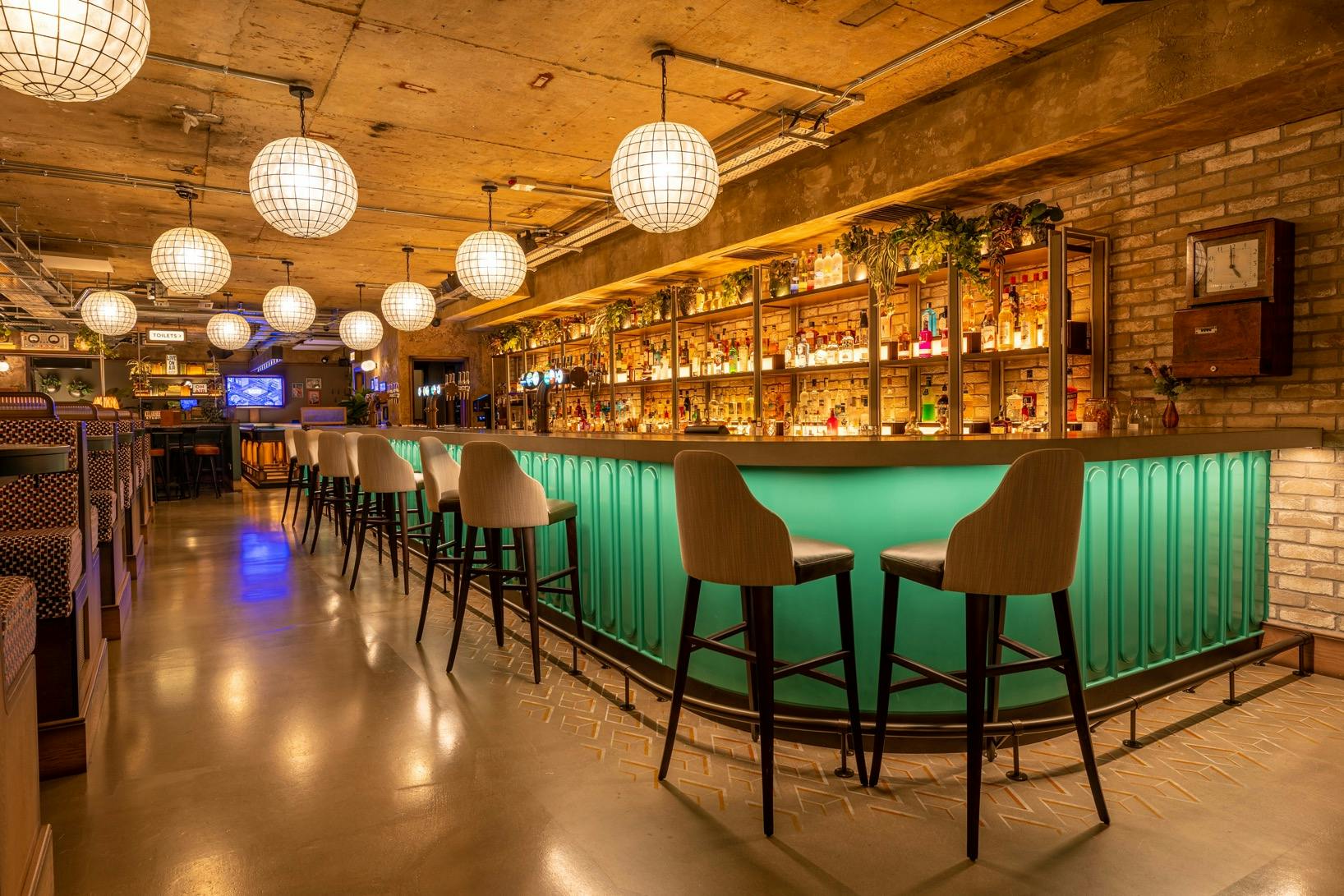 Stylish bar area with vibrant green counter at Electric Shuffle Leeds for networking events.