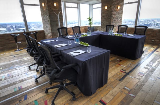 Modern meeting space with U-shaped table, natural light, ideal for corporate events.