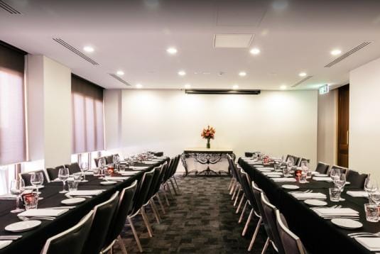 Elegant meeting room with black tablecloths, ideal for corporate events and conferences.