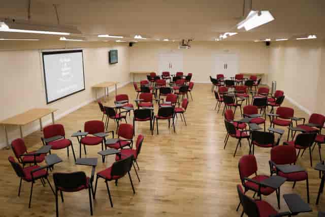 Versatile workshop space with red chairs and projector screen at Manor&Ashbury Resorts.