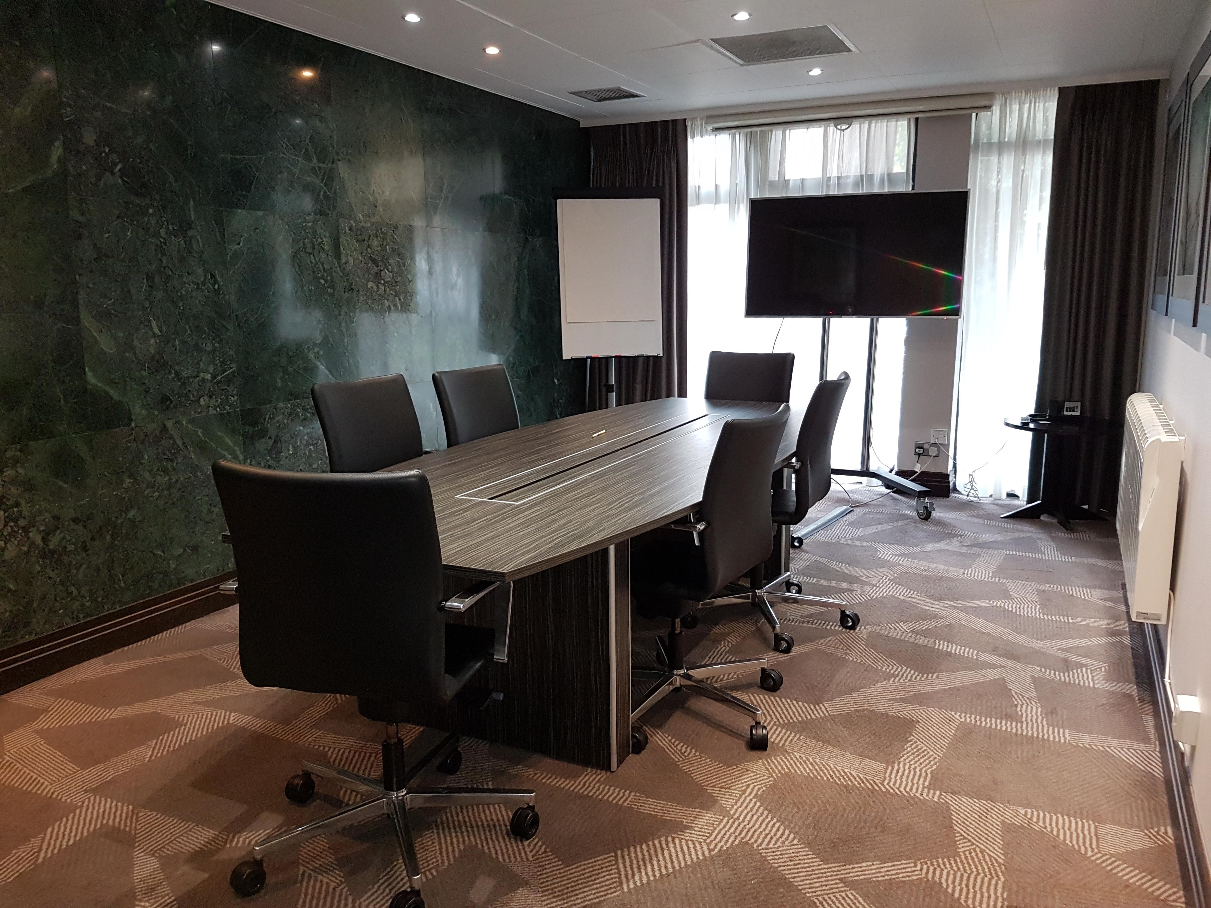 Modern meeting room in Perry Suite, DoubleTree London Ealing, with ergonomic chairs and large screen.