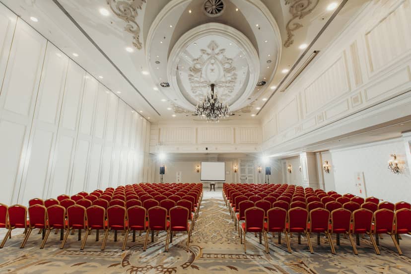 Premium Ballroom in Rixos Almaty, spacious conference venue with red chairs and chandelier.