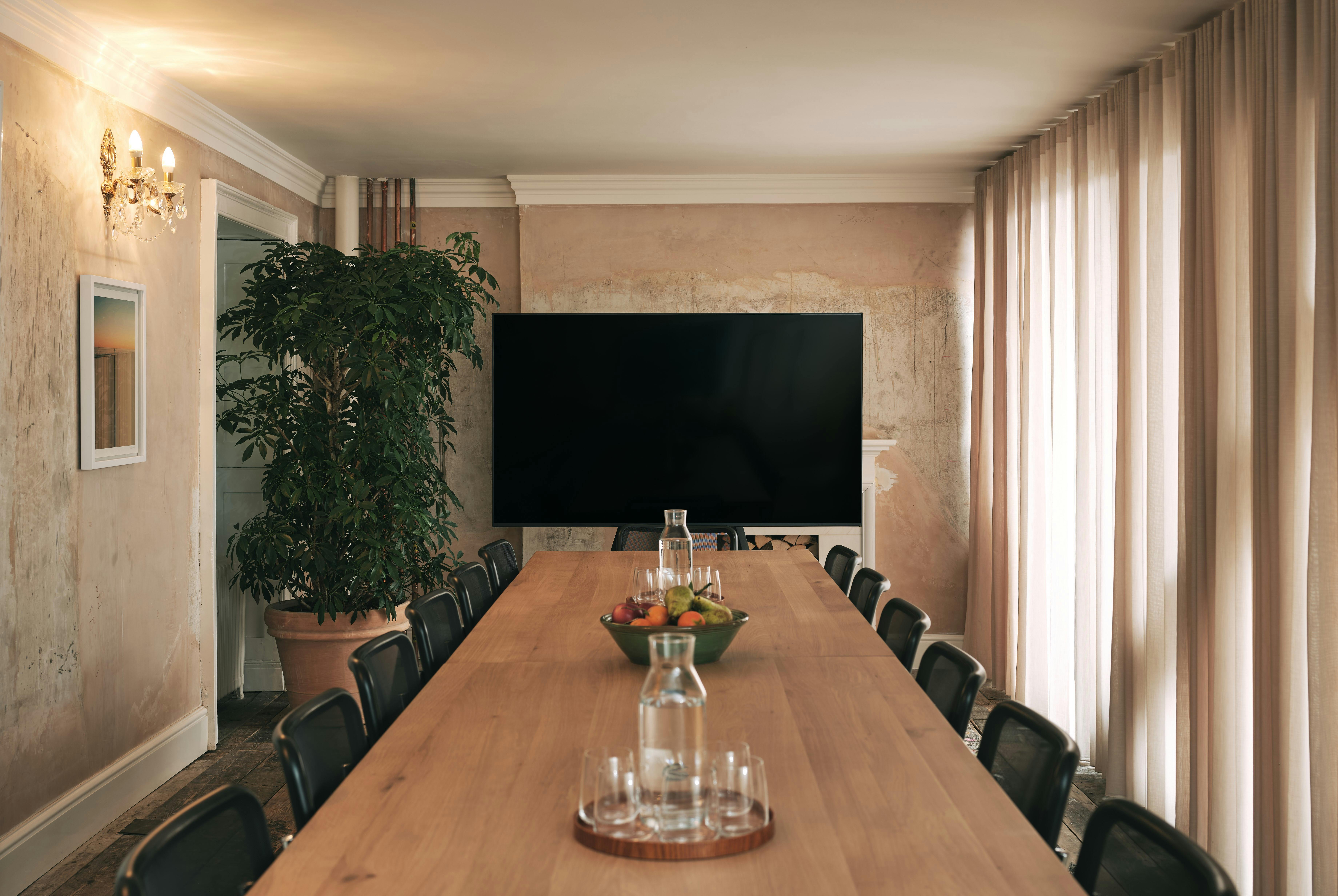 Meeting room with wooden table and greenery at Knotel Workclub, ideal for presentations.