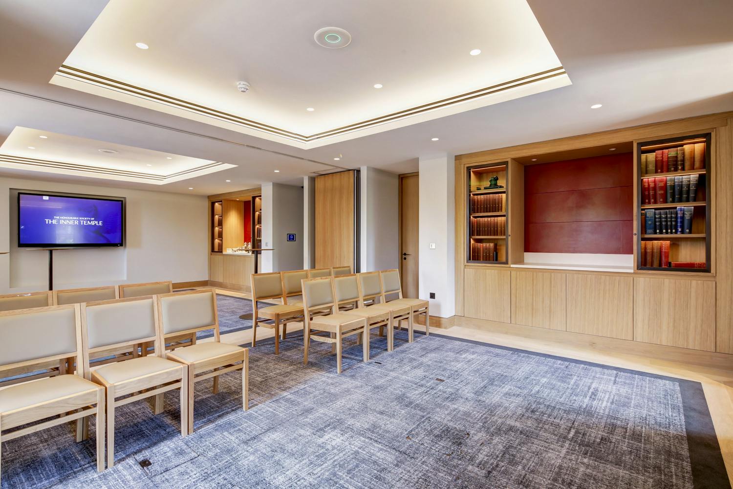 Intimate meeting space in The Inner Temple with minimalist wooden seating and presentation screen.