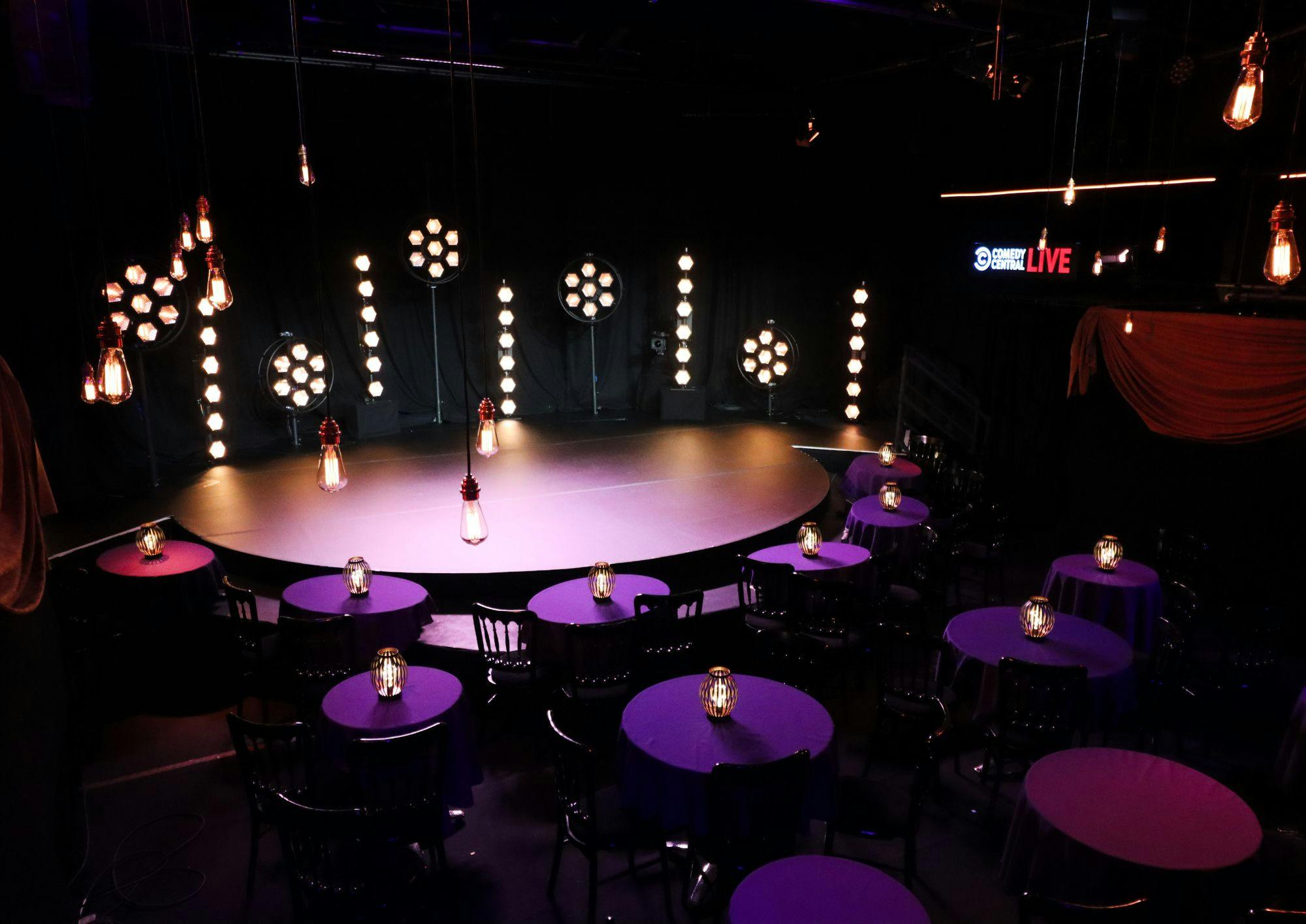 Stylish Pleasance Theatre event space with circular stage and purple tablecloths.