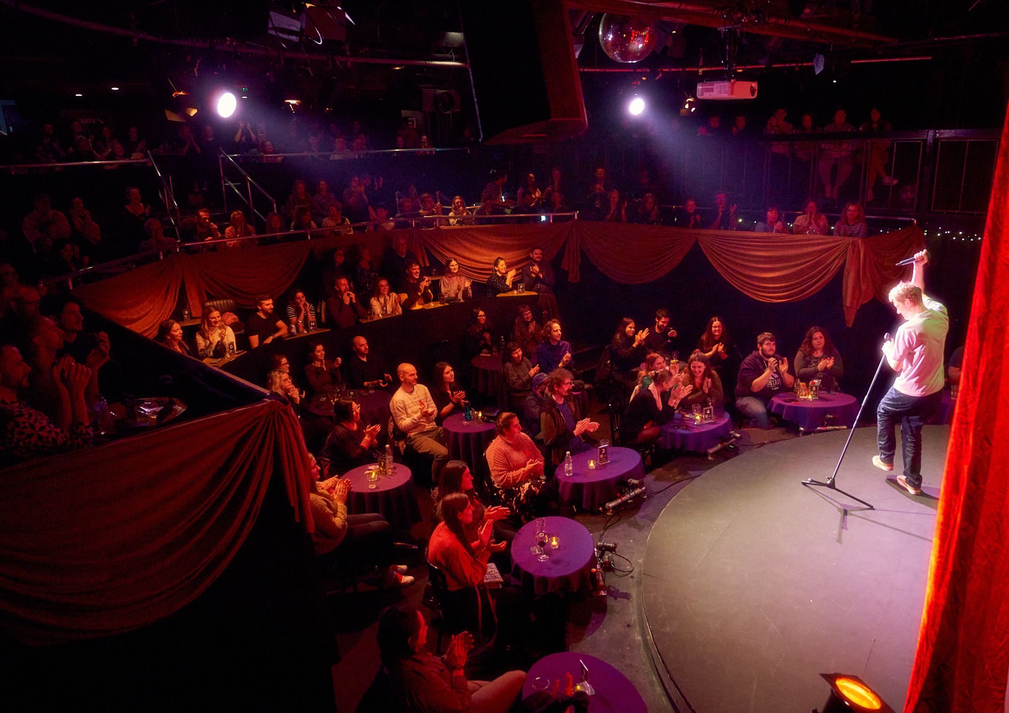 Vibrant Pleasance Theatre performance space with circular stage, ideal for comedy shows. - Banner