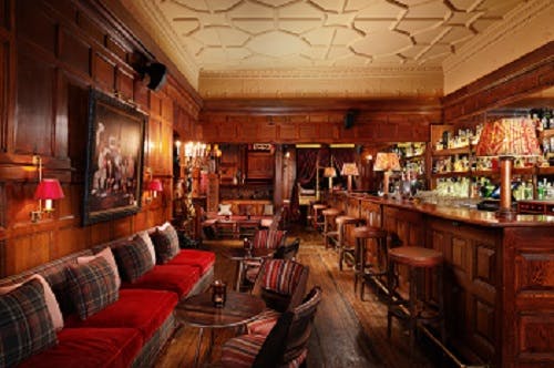 Cozy upscale bar with warm wood paneling, ideal for networking events and gatherings.