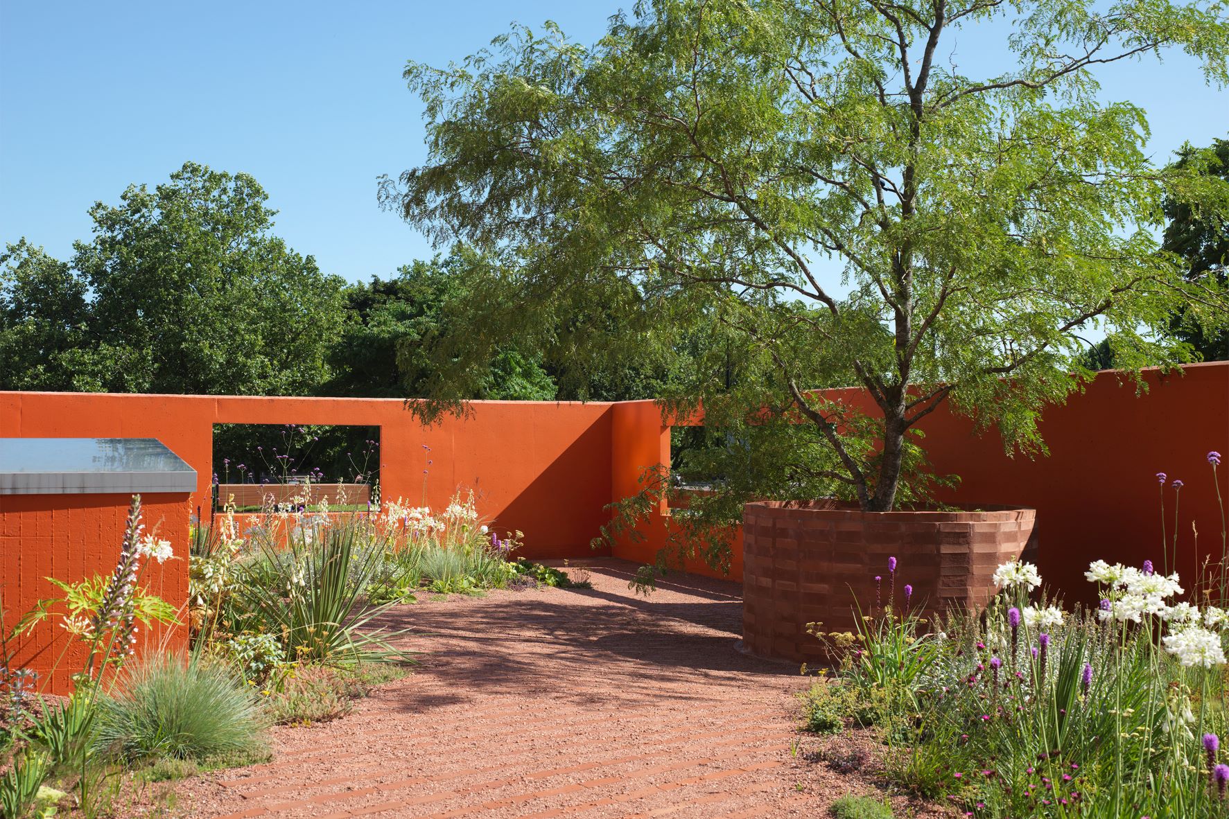 Vibrant outdoor event space at Forma HQ with warm orange walls and lush greenery. - Banner