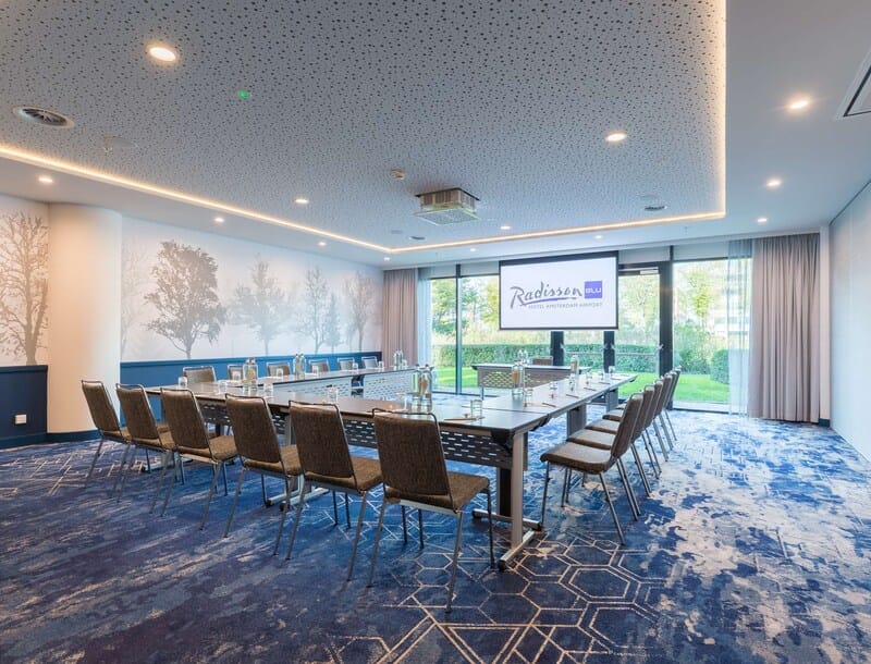Modern meeting room at Radisson Blu, Amsterdam Airport with large table and natural light.