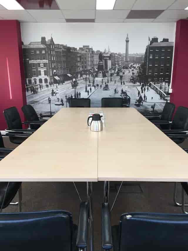 Modern meeting room with large table and cityscape backdrop for collaborative events.