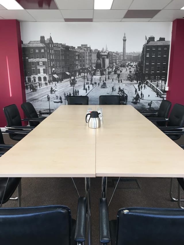 Modern meeting room with large table and cityscape backdrop for collaborative events.