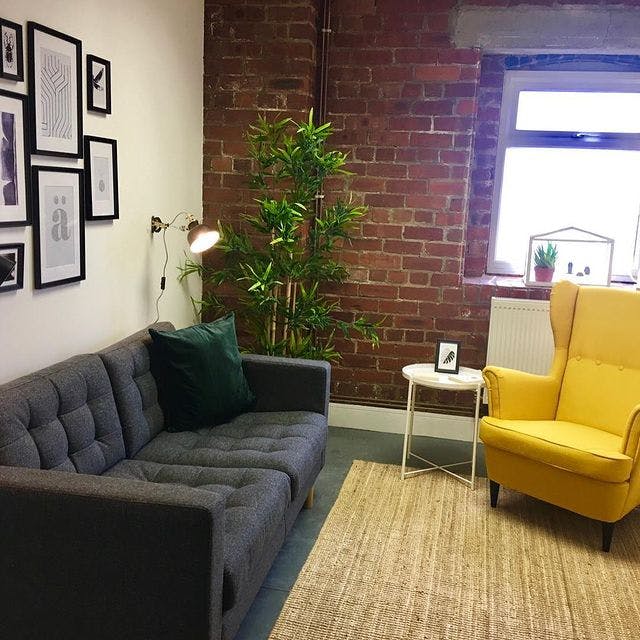 Cozy Basement Event Space with gray sofa and yellow armchair for meetings and brainstorming.