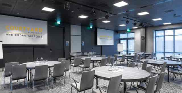 Modern meeting room with round tables for corporate events at Marriott Courtyard Amsterdam Airport.