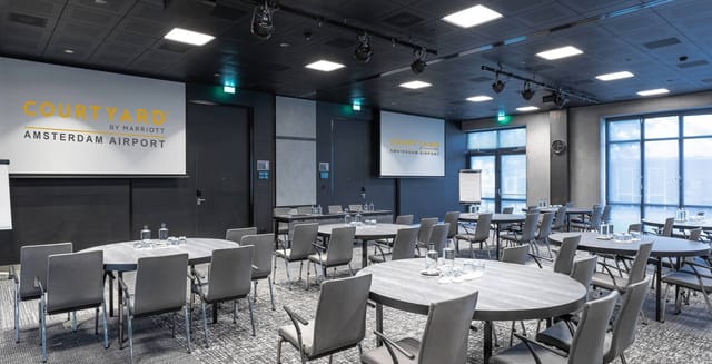 Modern meeting room with round tables for corporate events at Marriott Courtyard Amsterdam Airport.