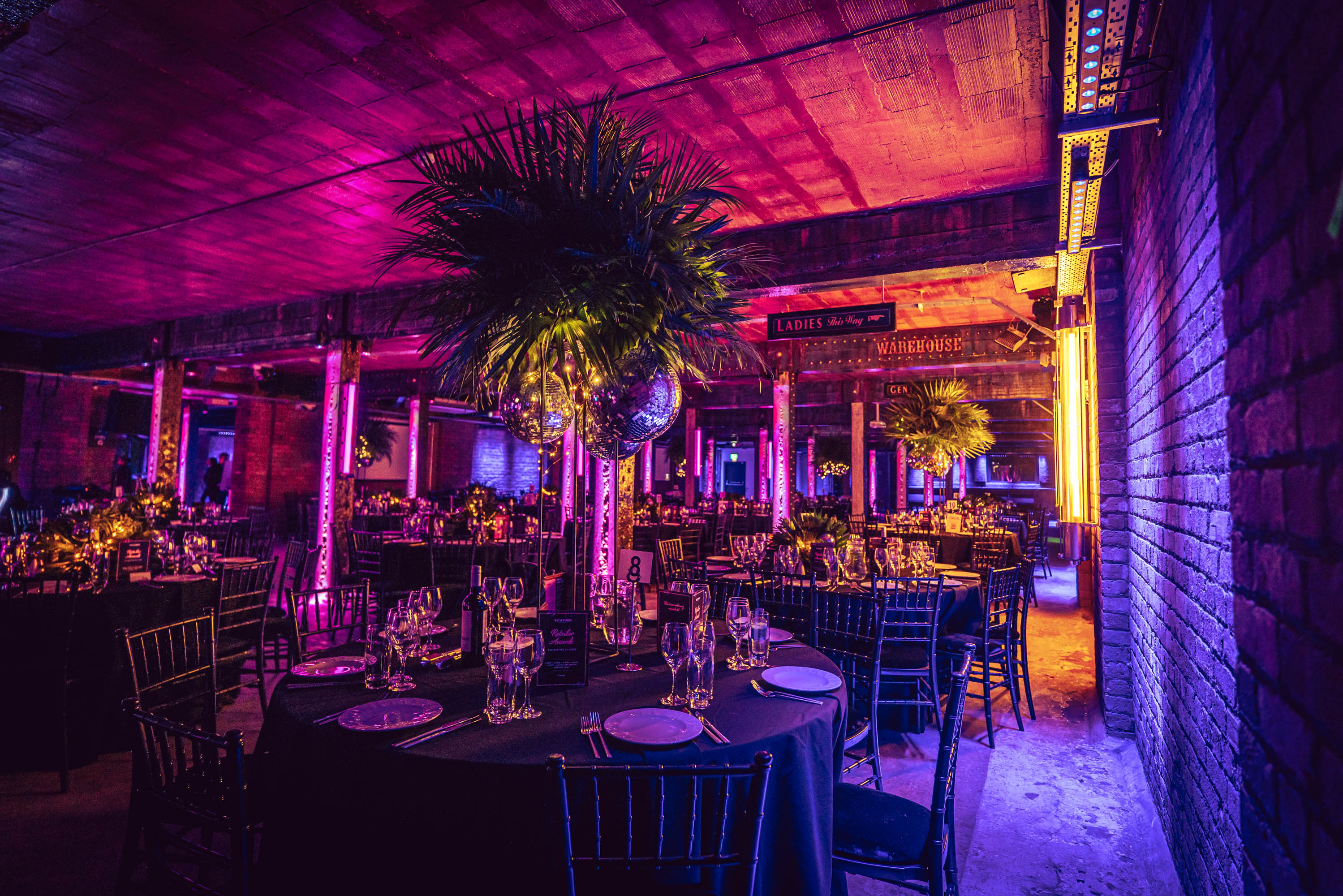 Elegant event space at Tobacco Stores with round tables and vibrant purple lighting. - Banner