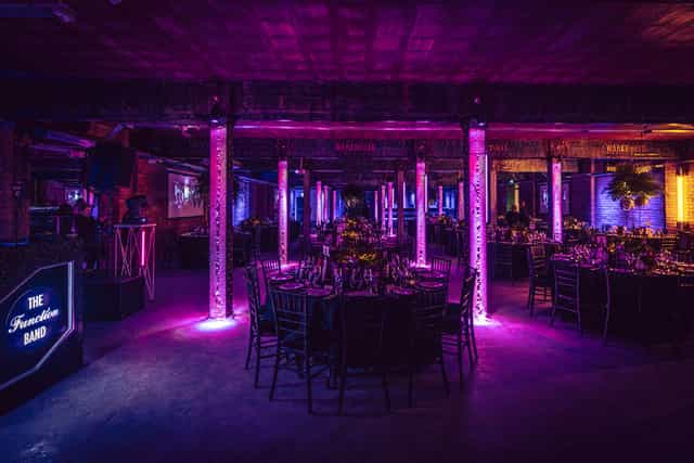 Elegant event space at Tobacco Stores, featuring round tables and vibrant lighting for corporate events.