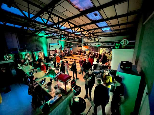 Brewery event space with vibrant attendees networking in an industrial setting.