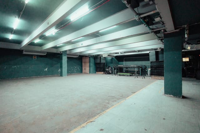 Spacious minimalist event venue with exposed beams, ideal for customizable gatherings.