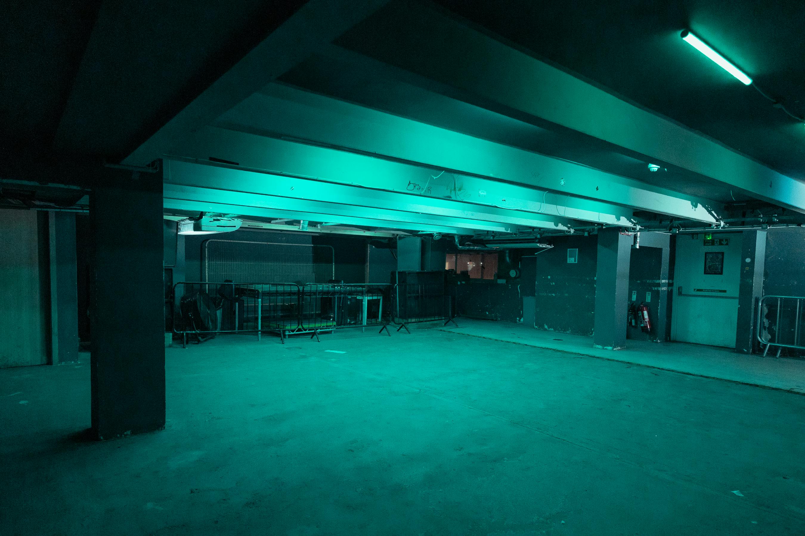 Versatile industrial event space with teal lighting at The Cause, perfect for parties and gatherings.