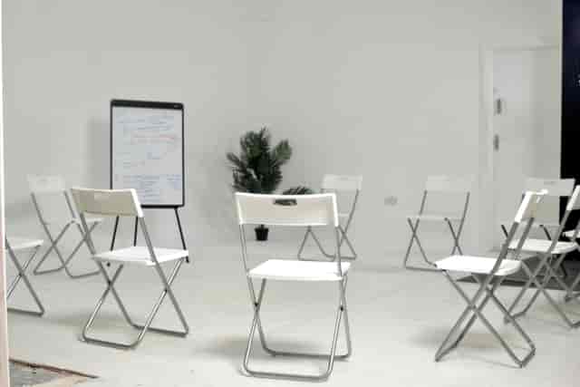 Minimalist white meeting room with circular chairs, ideal for workshops and brainstorming.