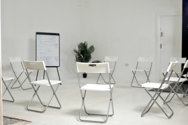 Minimalist white meeting room with circular chairs, ideal for workshops and brainstorming.