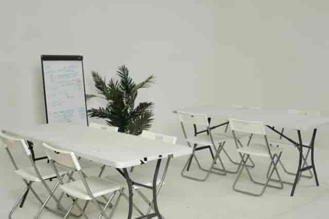 Minimalist white meeting room with folding tables for workshops and brainstorming sessions.