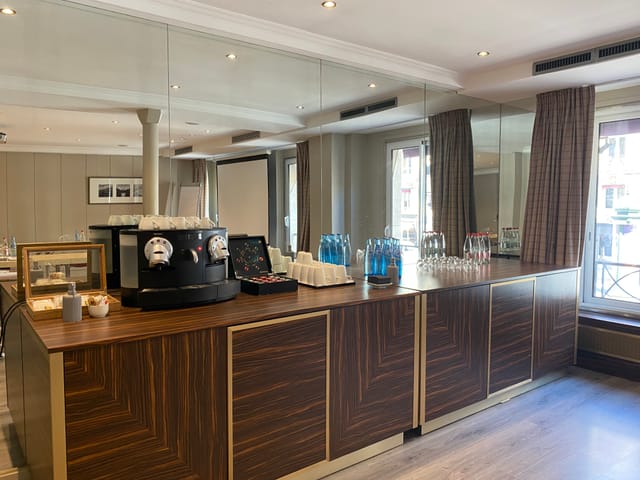 Elegant meeting space at Hotel Edouard 7 with polished wooden refreshment station.