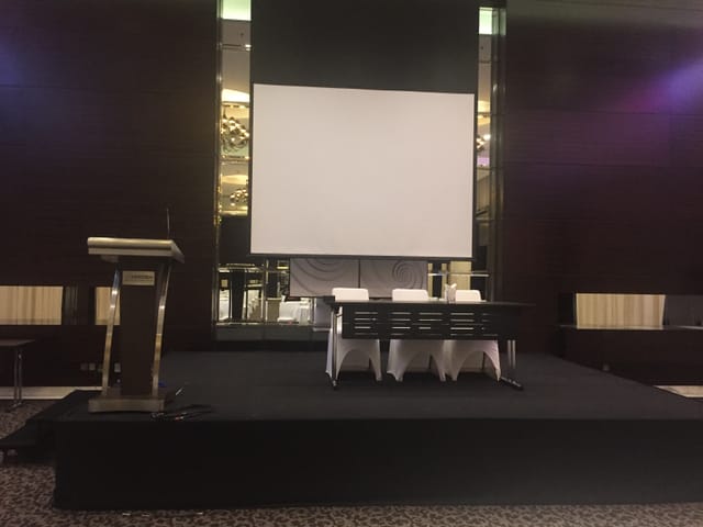 Conference stage setup at Le Meridien Dubai with podium and presentation screen.