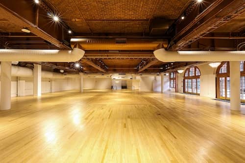 Spacious event venue with polished floors and natural light for conferences and gatherings.