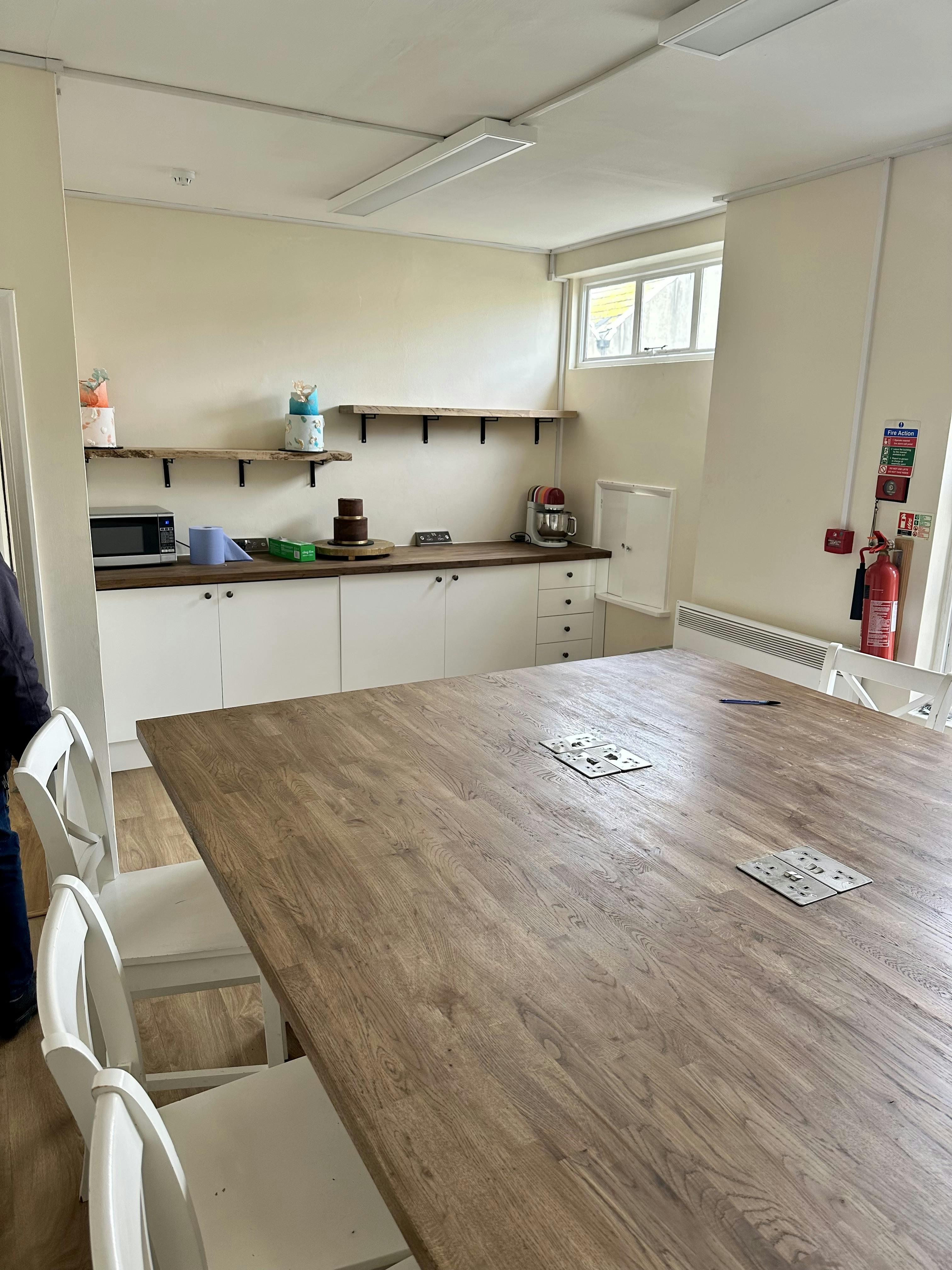 Bright meeting space with large wooden table, perfect for workshops and team meetings.