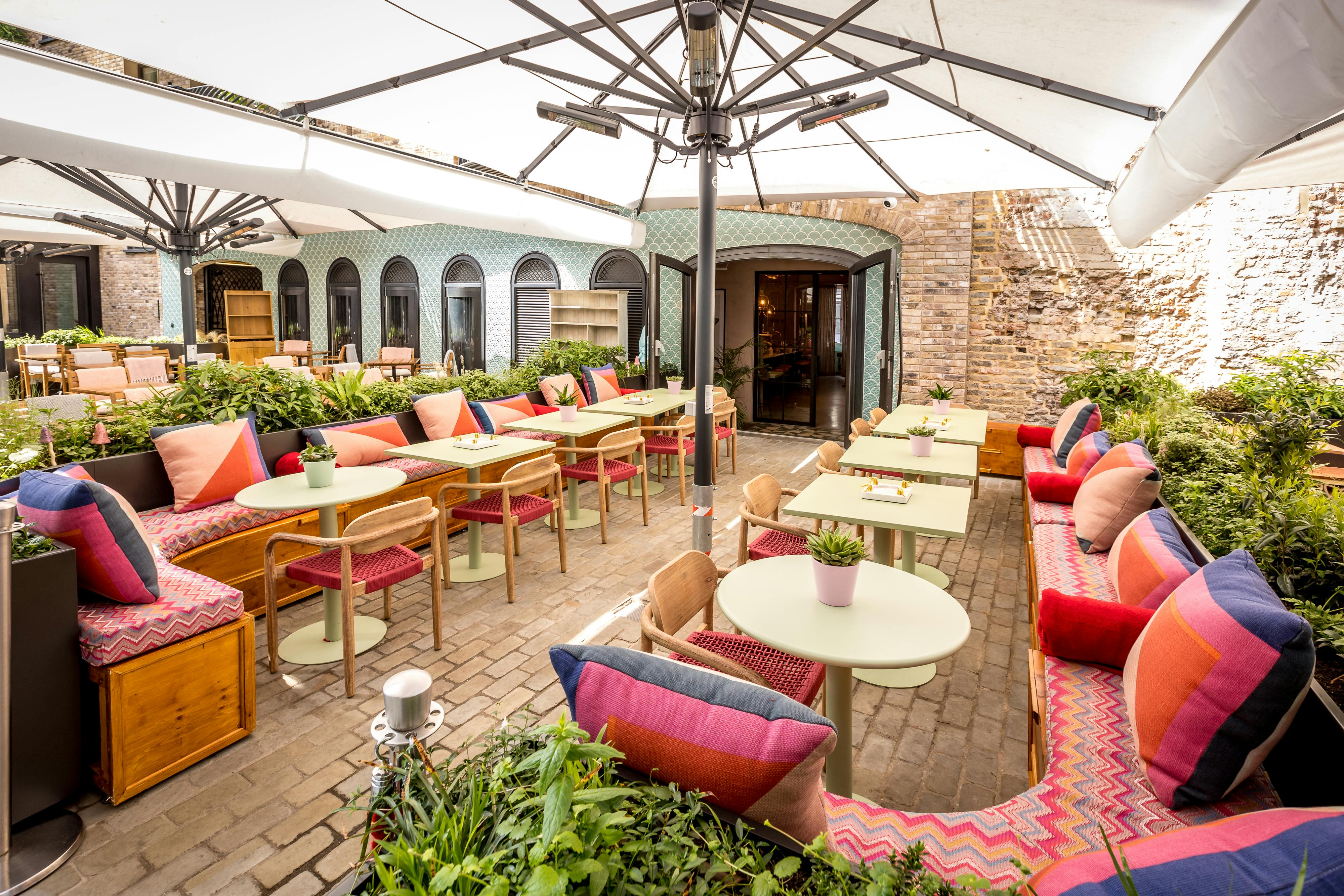 Vibrant outdoor event space at The Little Scarlet Door with colorful seating and greenery.