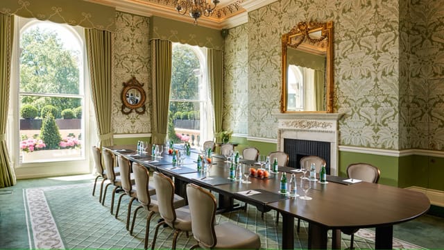 Sophisticated meeting room with lush green walls, perfect for corporate events.