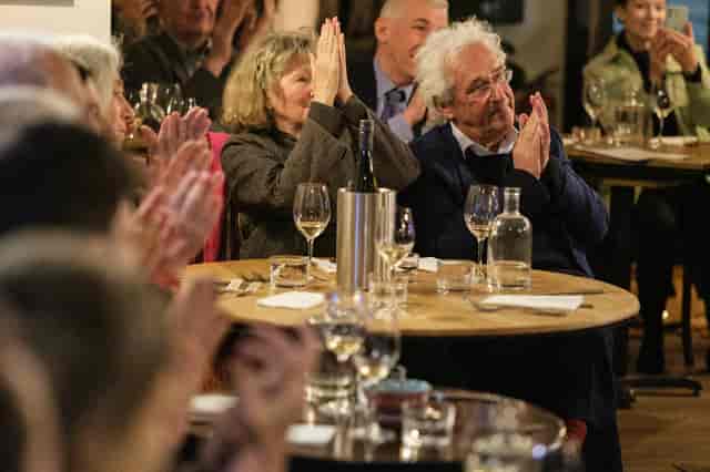 Engaged audience at Vienna Salon event with dining tables and wine glasses.