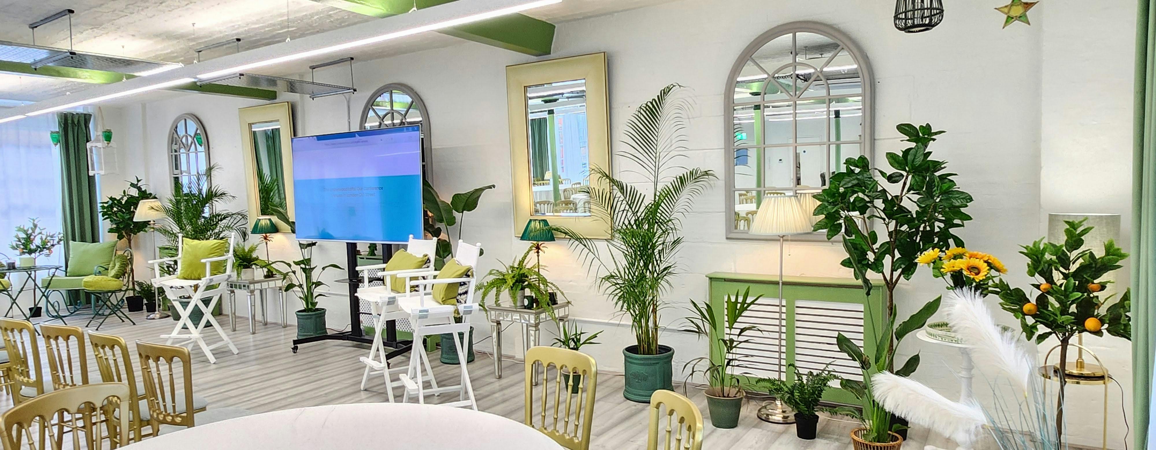 Modern meeting space in The Palm Room, featuring greenery and tech setup for events.