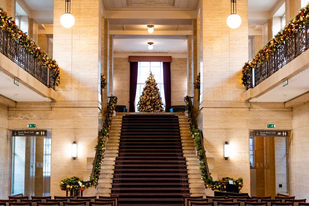 "Senate House Christmas party venue with a lit tree and elegant staircase decorations."