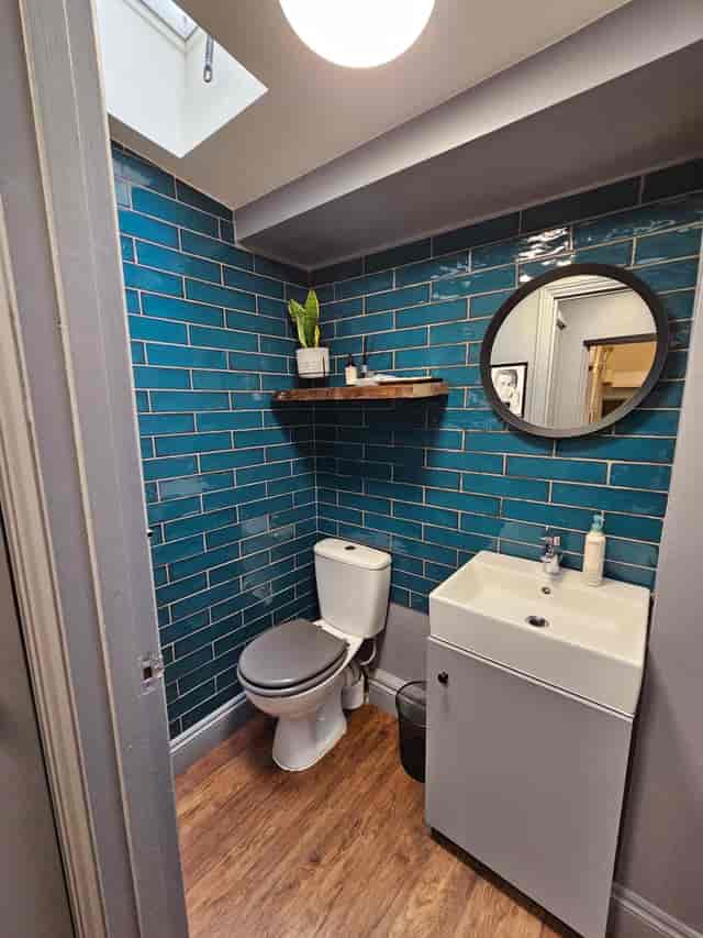 Stylish turquoise tiled restroom with sleek mirror for events and meetings.