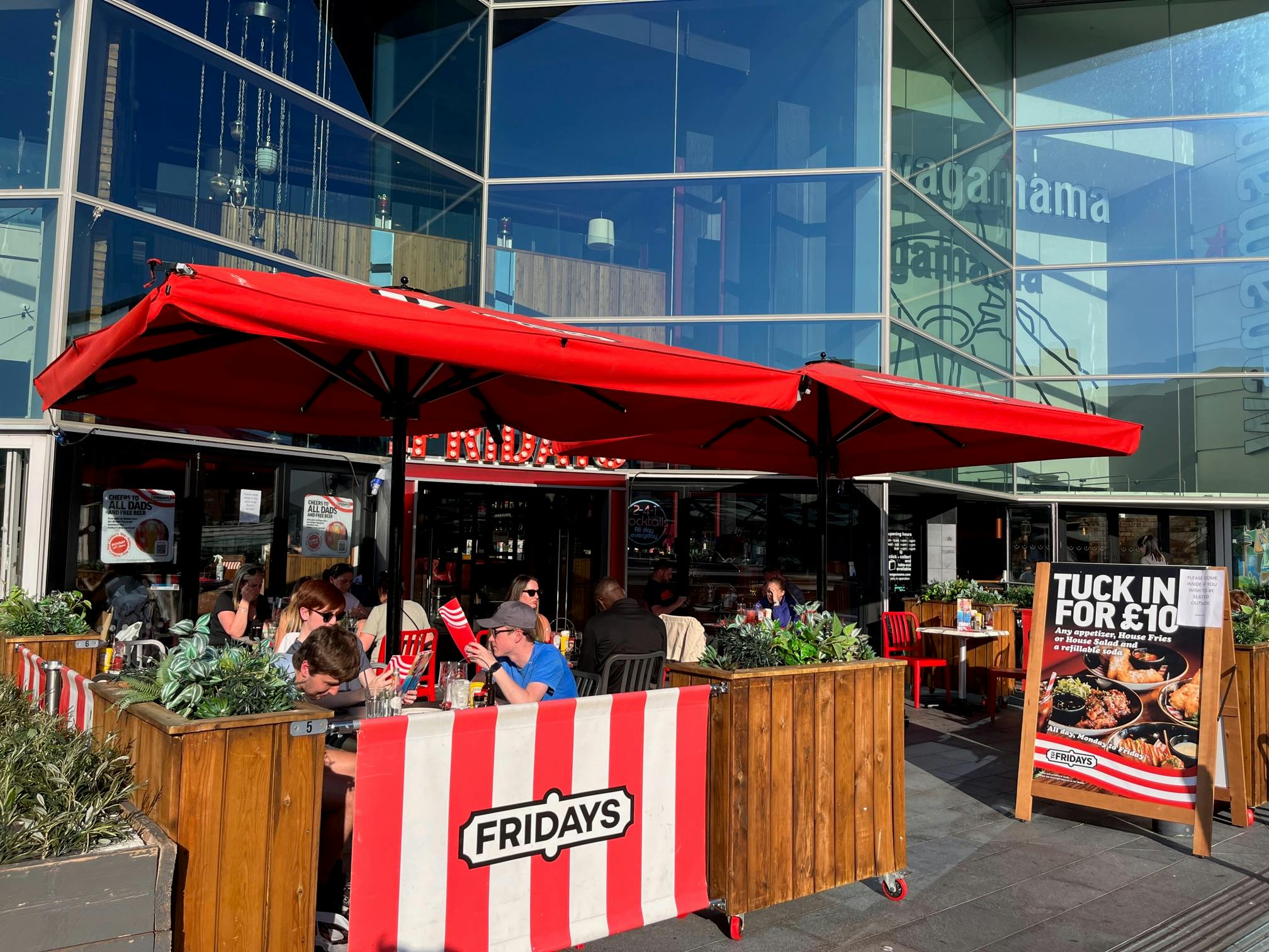 Vibrant outdoor dining area with red umbrellas in Liverpool One for casual events.
