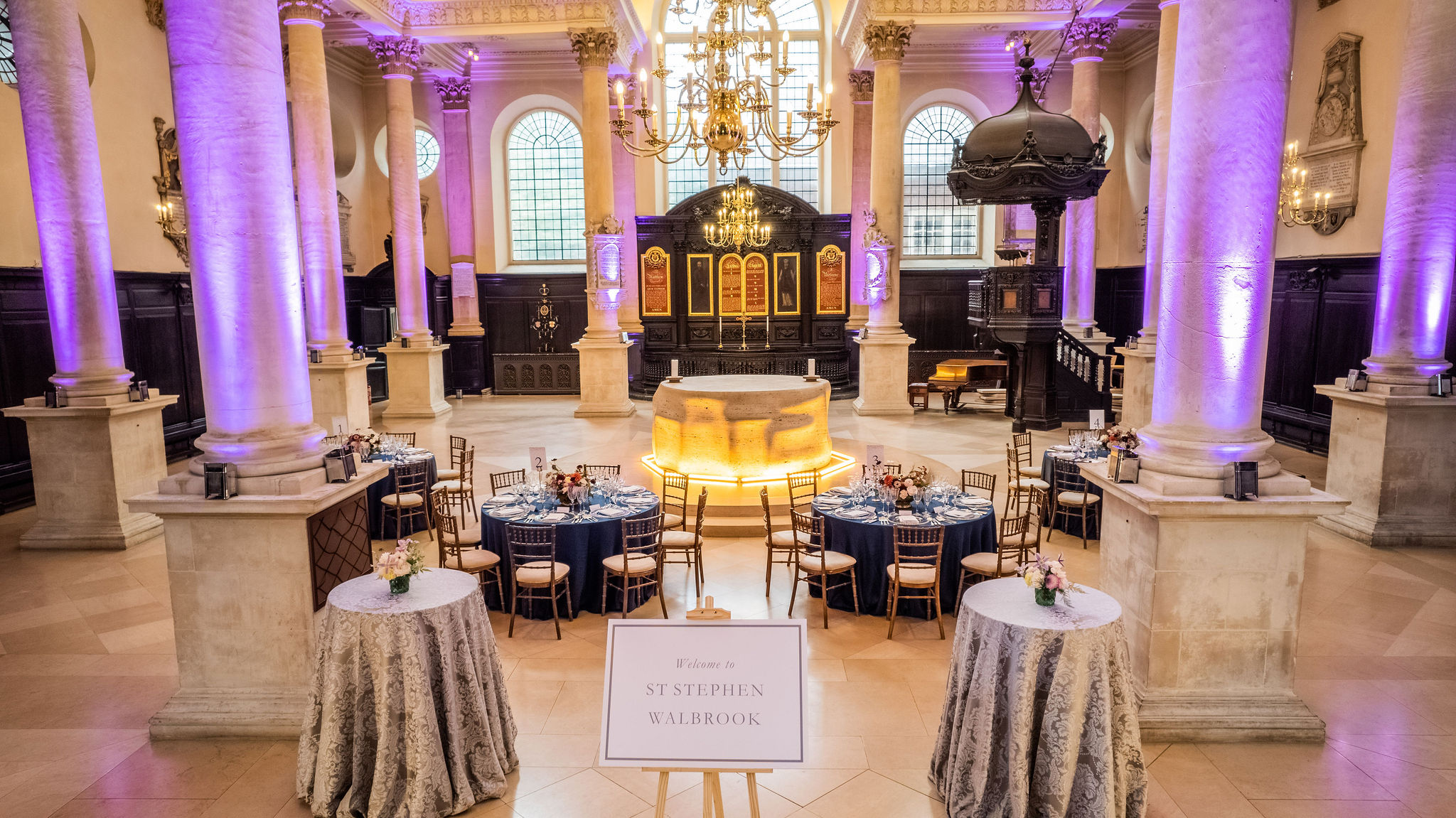 Elegant event space with round tables and purple lighting at St Stephen Walbrok gala.