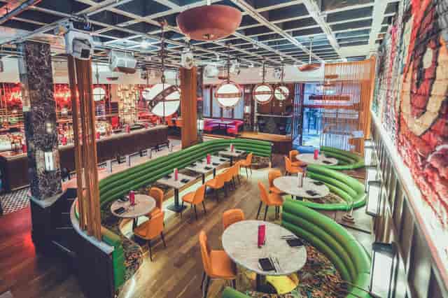Modern event space with green booths and marble tables, perfect for networking events.