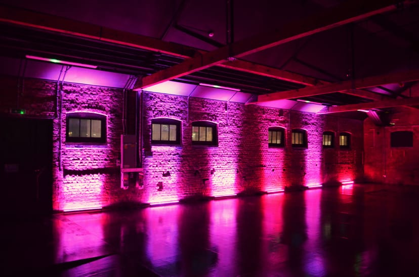 Versatile event space in Camden with industrial vibe and dynamic purple lighting.