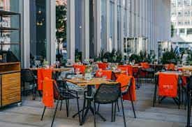 Vibrant dining setup with orange linens at The Anthologist event space, ideal for gatherings.