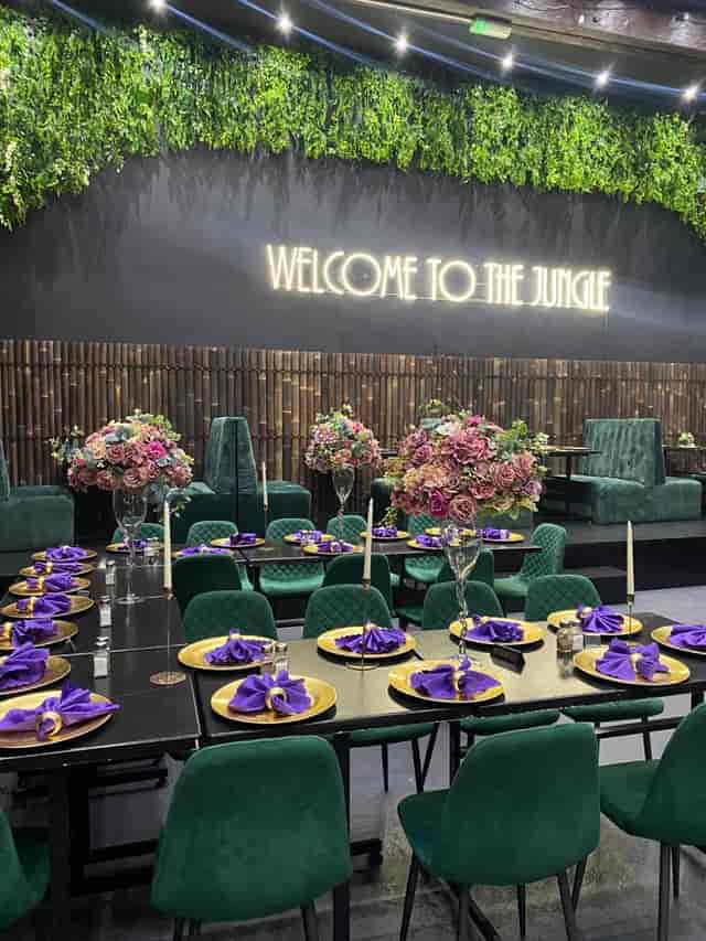 Elegant event space at Jungle Bar & Grill with purple napkins and neon sign.