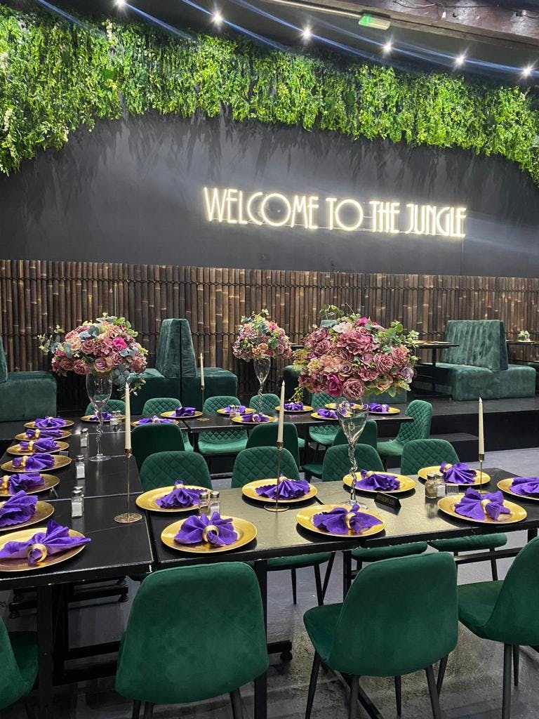 Upscale event space at Jungle Bar & Grill with floral centerpieces and neon sign.