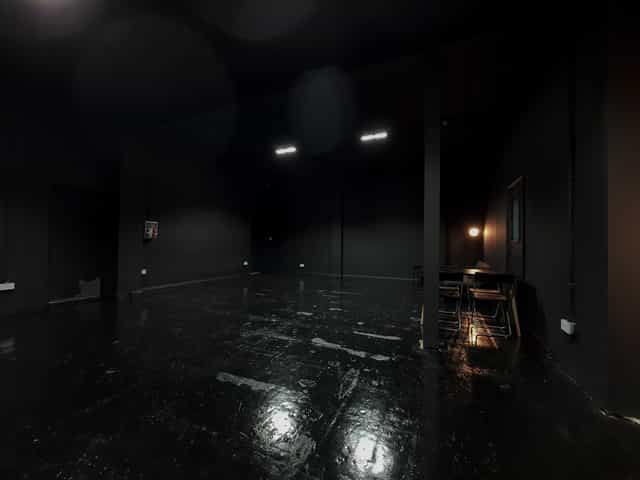Versatile minimalist event space with dark walls for creative meetings and workshops.