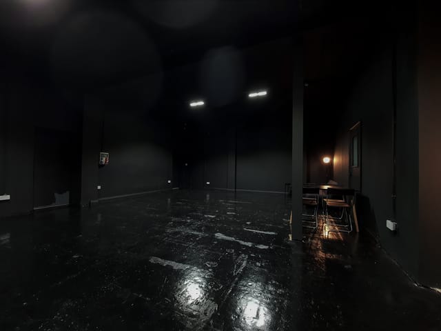 Versatile minimalist event space with dark walls for creative meetings and workshops.