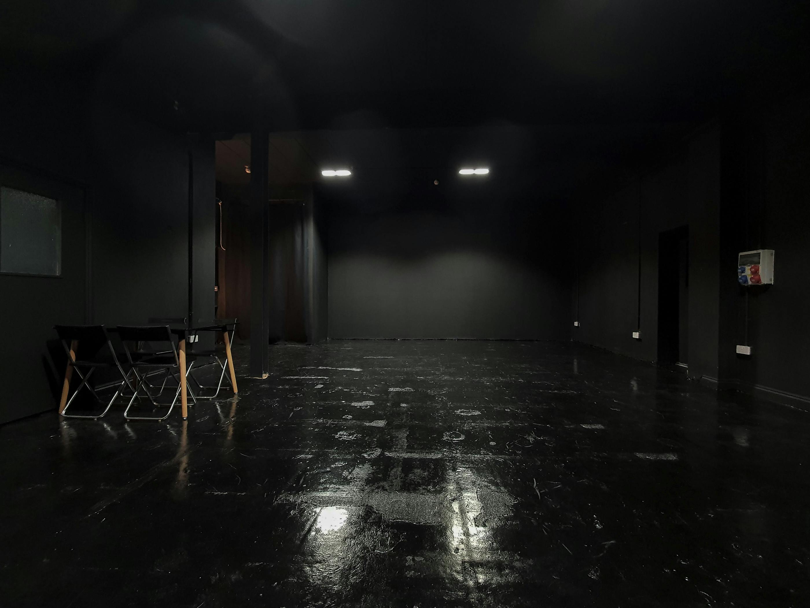 Versatile minimalist event space with sleek black interior for workshops and gatherings.